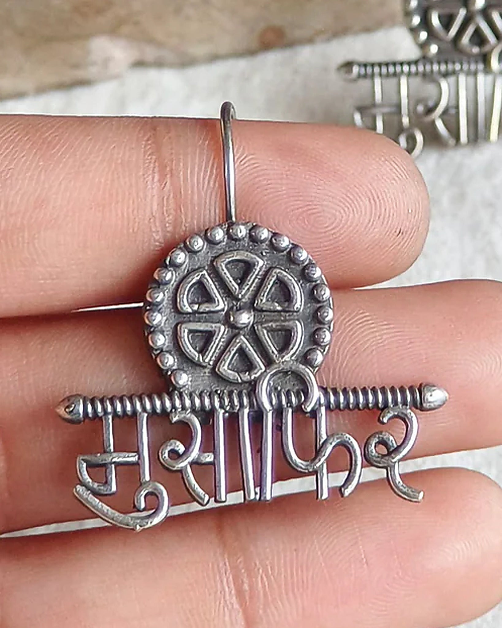 Oxidised silver-look brass drop earrings with the Devanagari word मुसाफ़िर beneath a spoked wheel