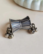 Oxidised silver-look brass statement ring shaped like a damru drum with small ghungroo bells at each end
