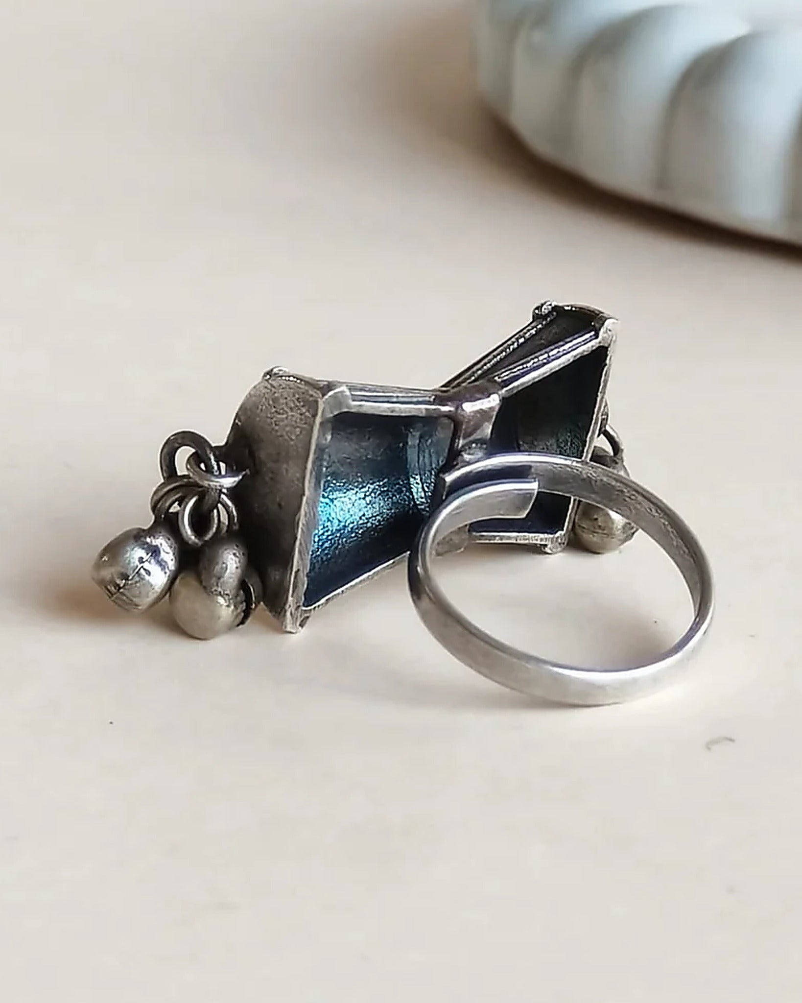 Oxidised silver-look brass statement ring shaped like a damru drum with small ghungroo bells at each end