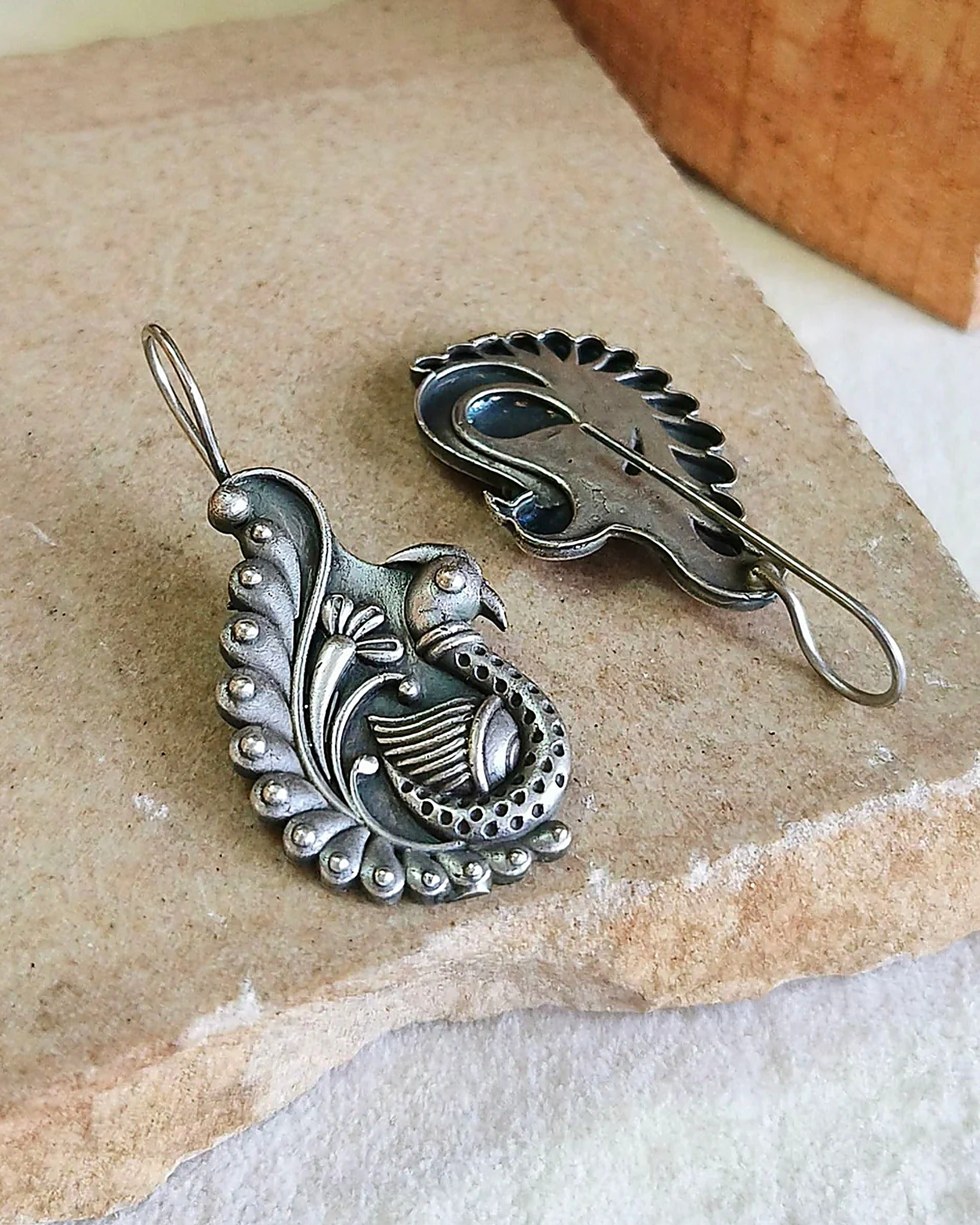 Oxidised silver-look brass drop earrings shaped as a peacock with a spiralled tail