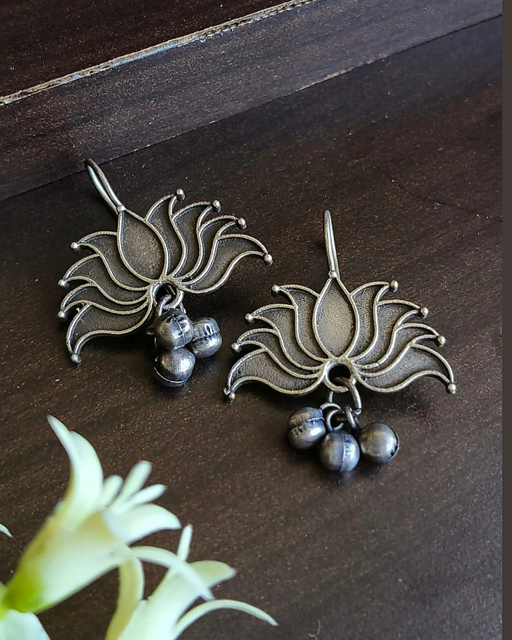 Oxidised silver-look brass drop earrings shaped as an open lotus with small ghungroo bells beneath