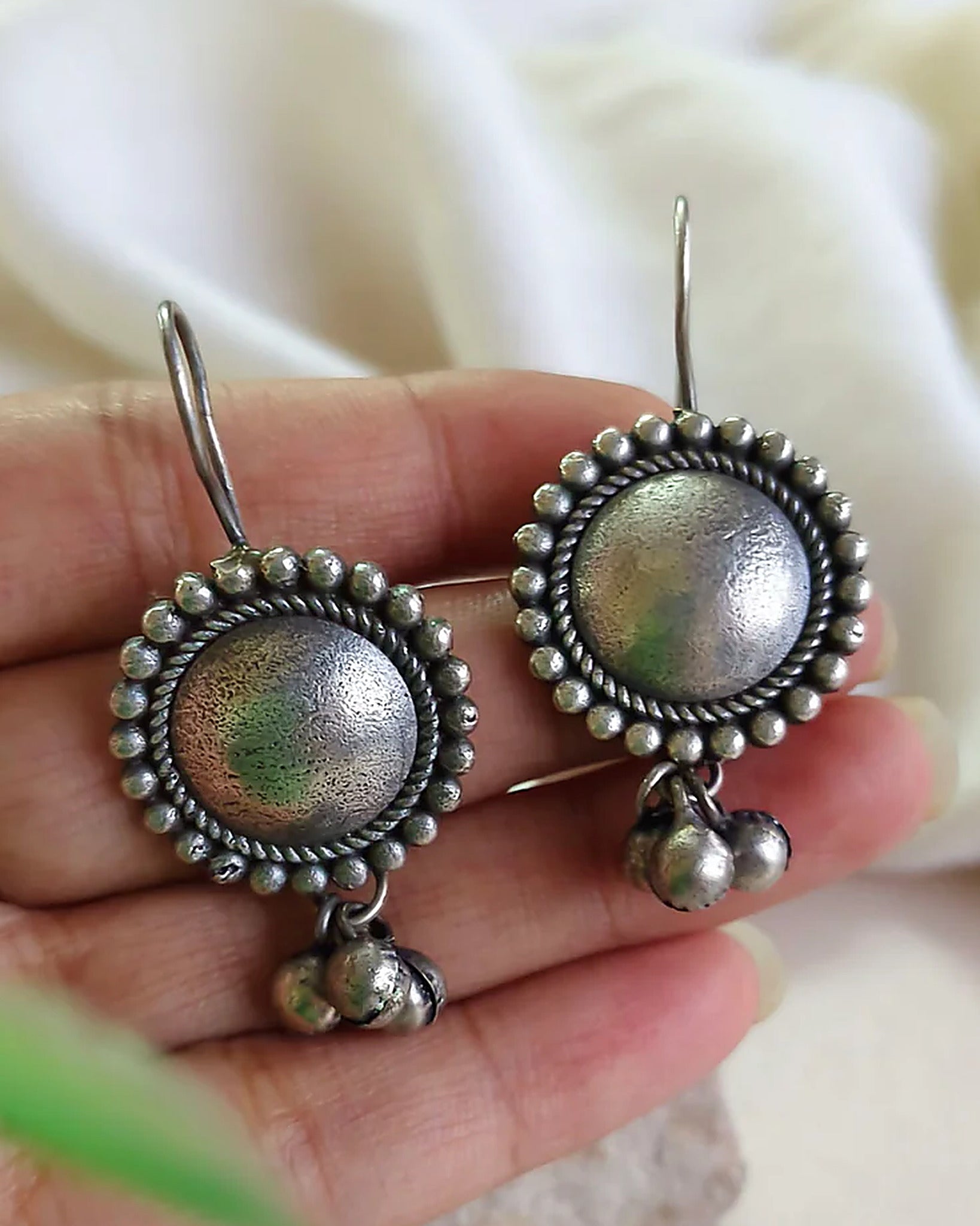 Oxidised silver-look brass drop earrings with a domed centre in a beaded halo and small ghungroo bells