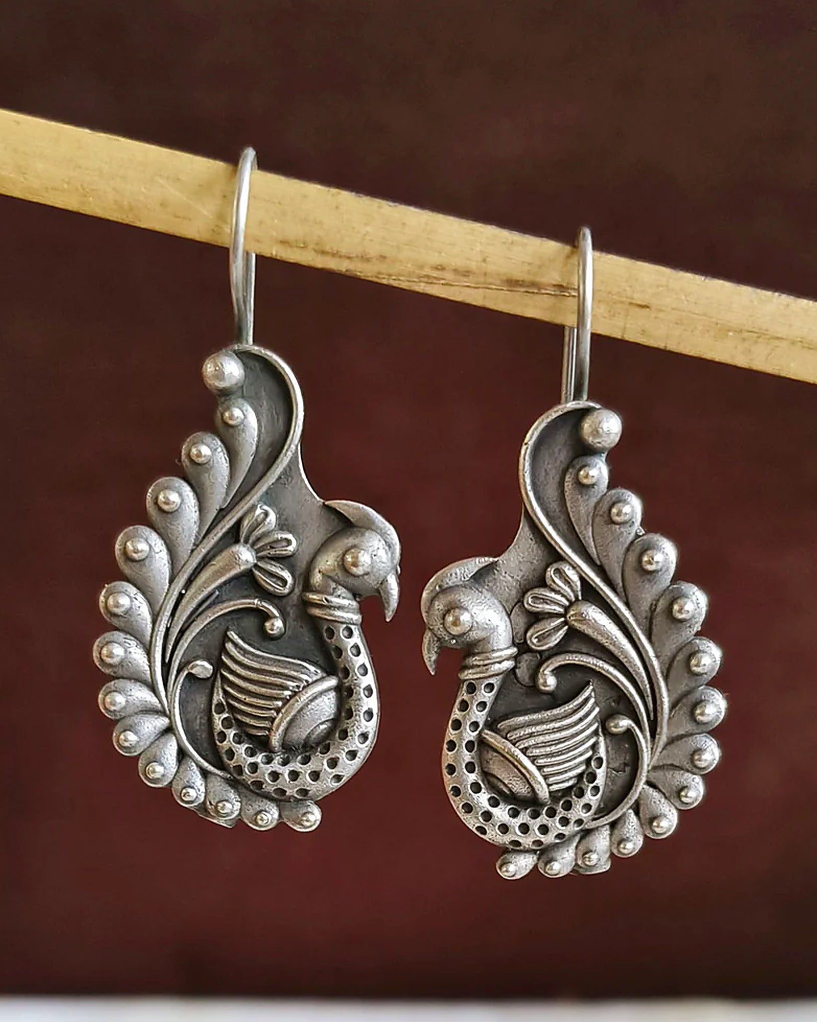 Oxidised silver-look brass drop earrings shaped as a peacock with a spiralled tail