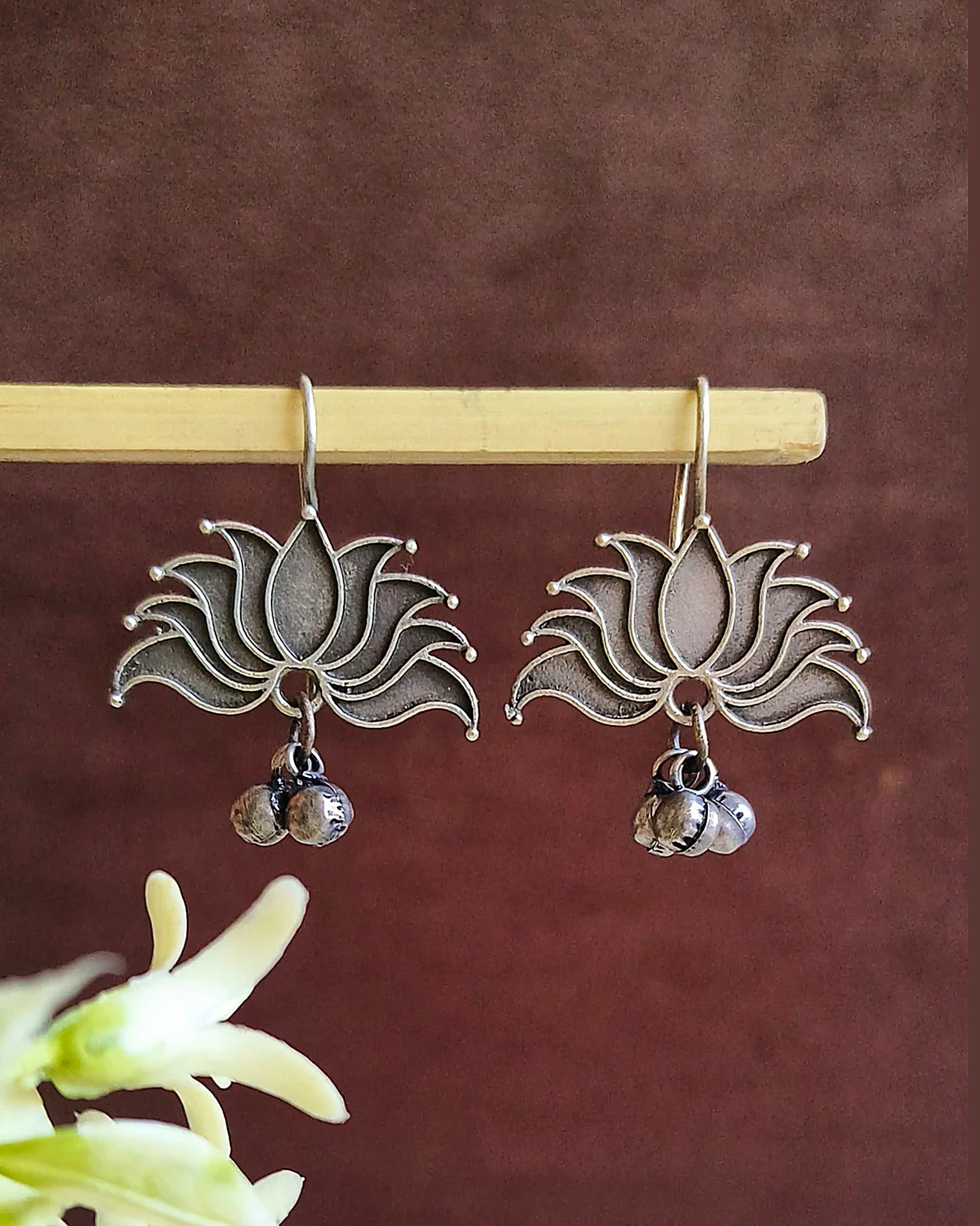 Oxidised silver-look brass drop earrings shaped as an open lotus with small ghungroo bells beneath