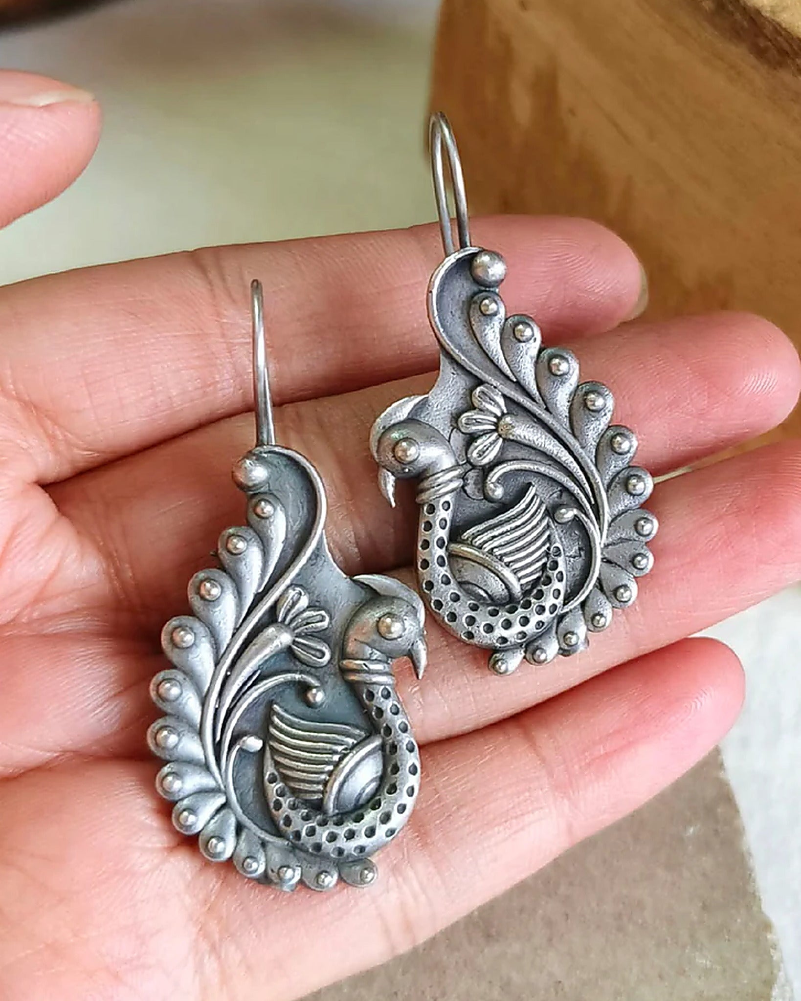Oxidised silver-look brass drop earrings shaped as a peacock with a spiralled tail