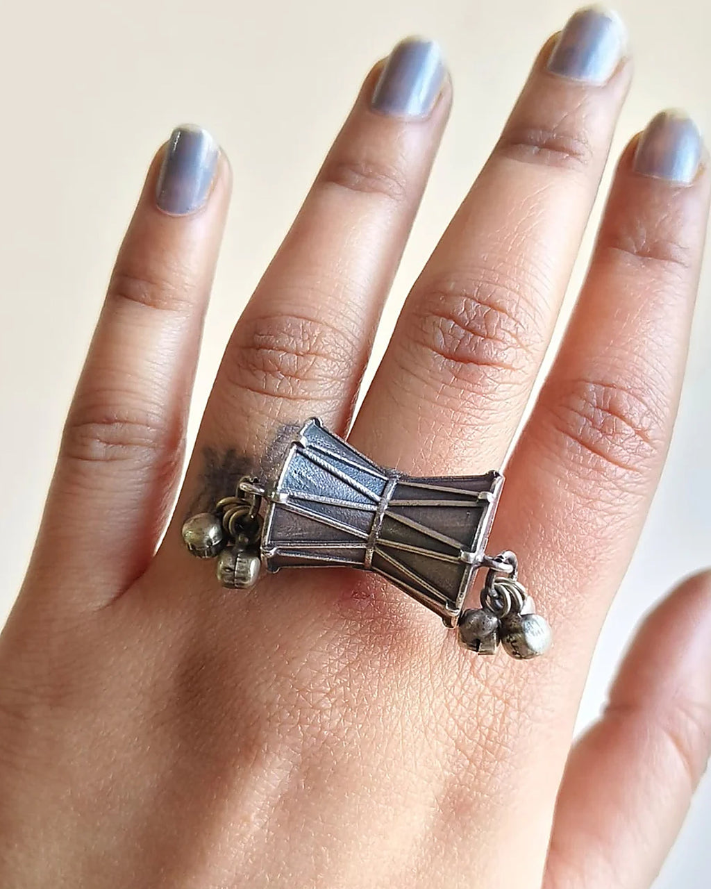 Oxidised silver-look brass statement ring shaped like a damru drum with small ghungroo bells at each end