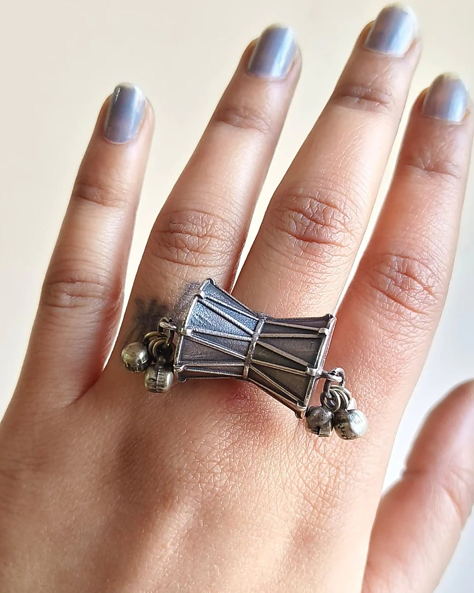 Oxidised silver-look brass statement ring shaped like a damru drum with small ghungroo bells at each end