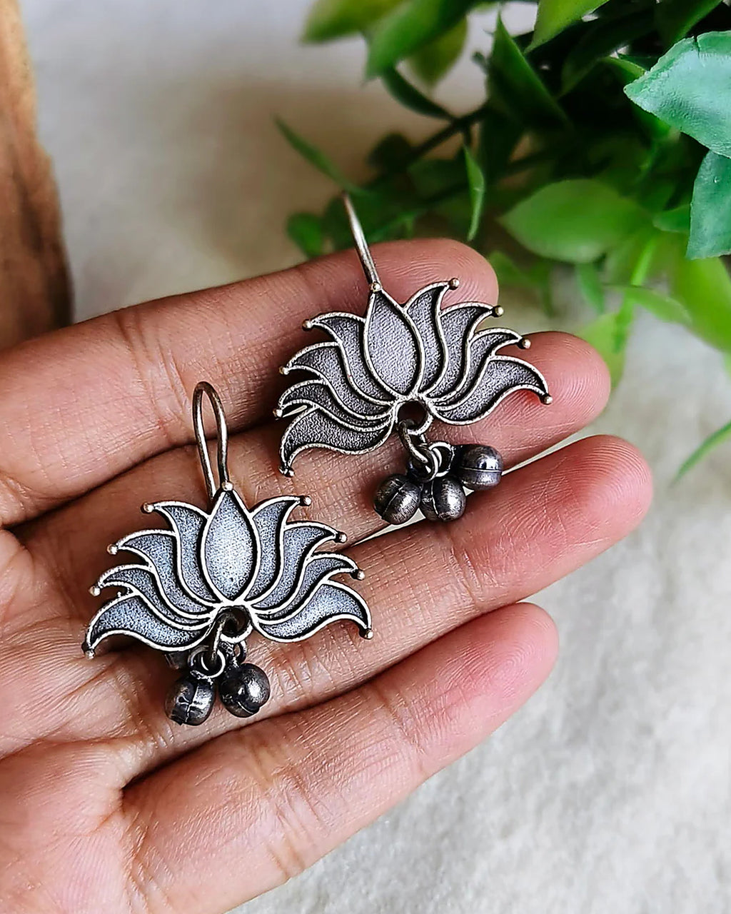 Oxidised silver-look brass drop earrings shaped as an open lotus with small ghungroo bells beneath