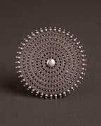 Close-up of the Nishan concentric disc ring on charcoal, showing the fine beaded granulation and smooth domed centre