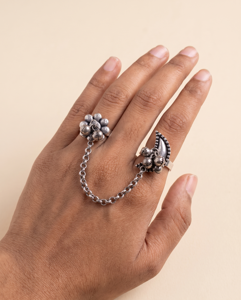 Pushkara two-finger ring worn on two fingers, the silver chain draping across the back of the hand