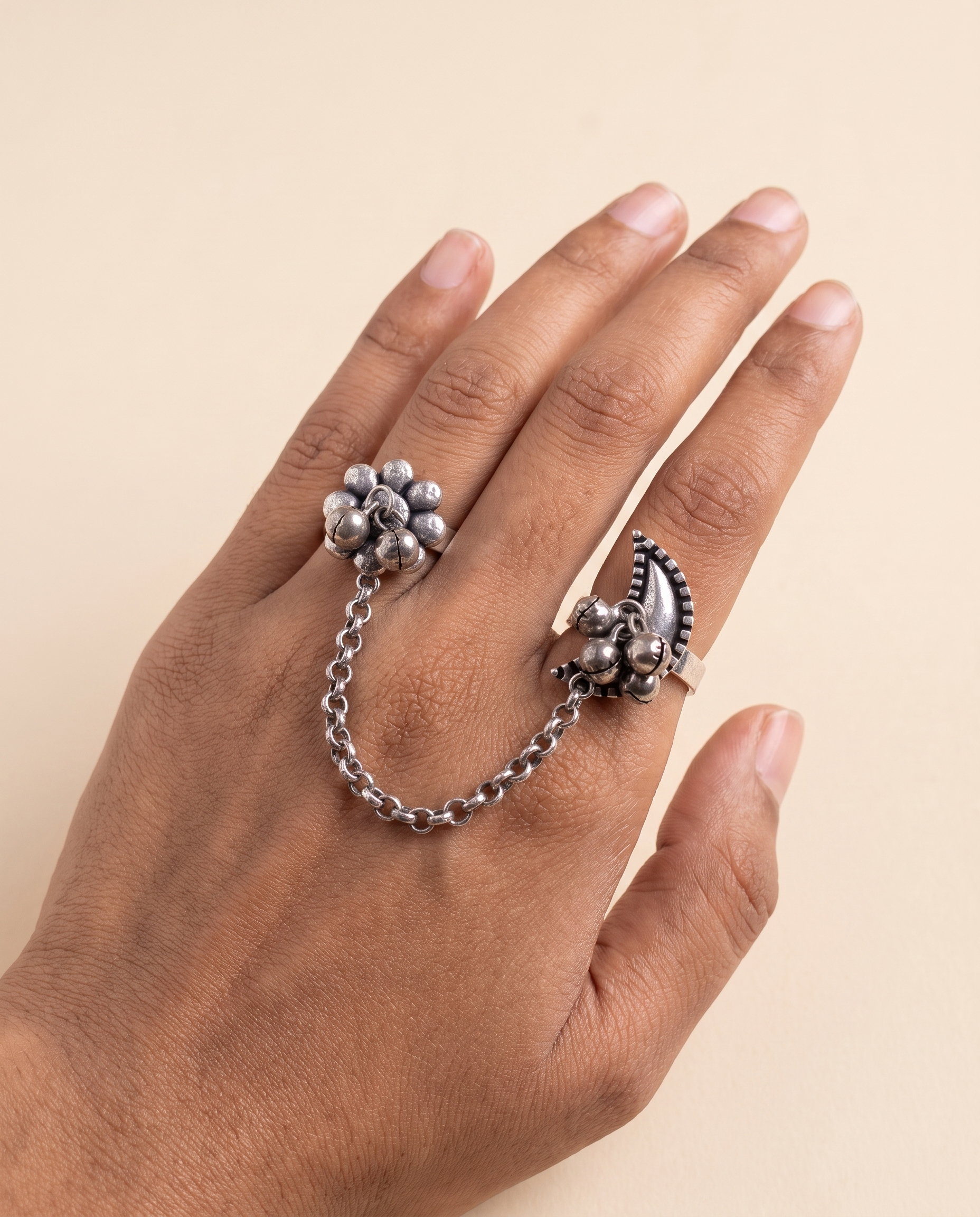 Pushkara two-finger ring worn on two fingers, the silver chain draping across the back of the hand