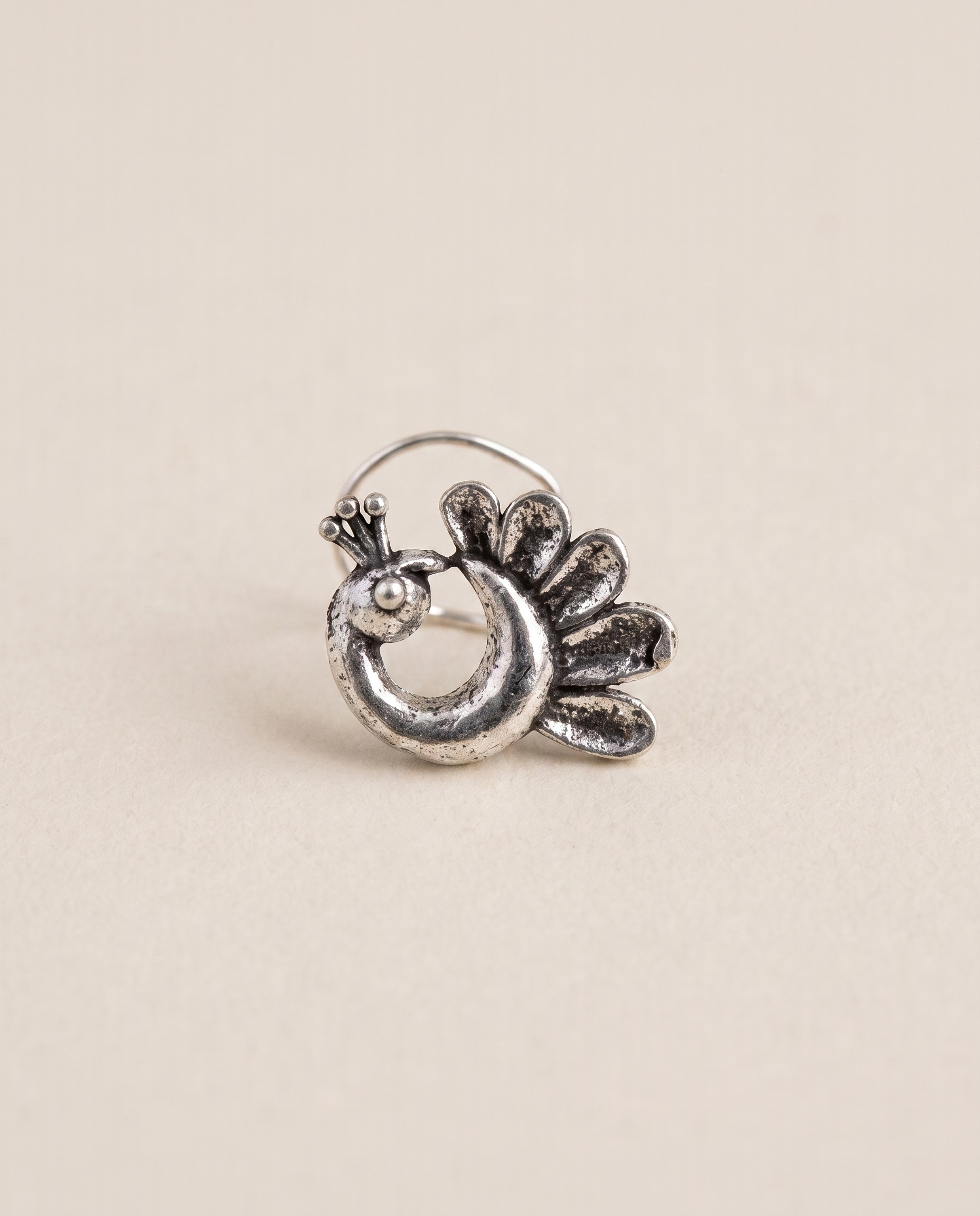 Morni oxidised silver-look peacock piercing nose pin with a fanned petal tail and beaded crest