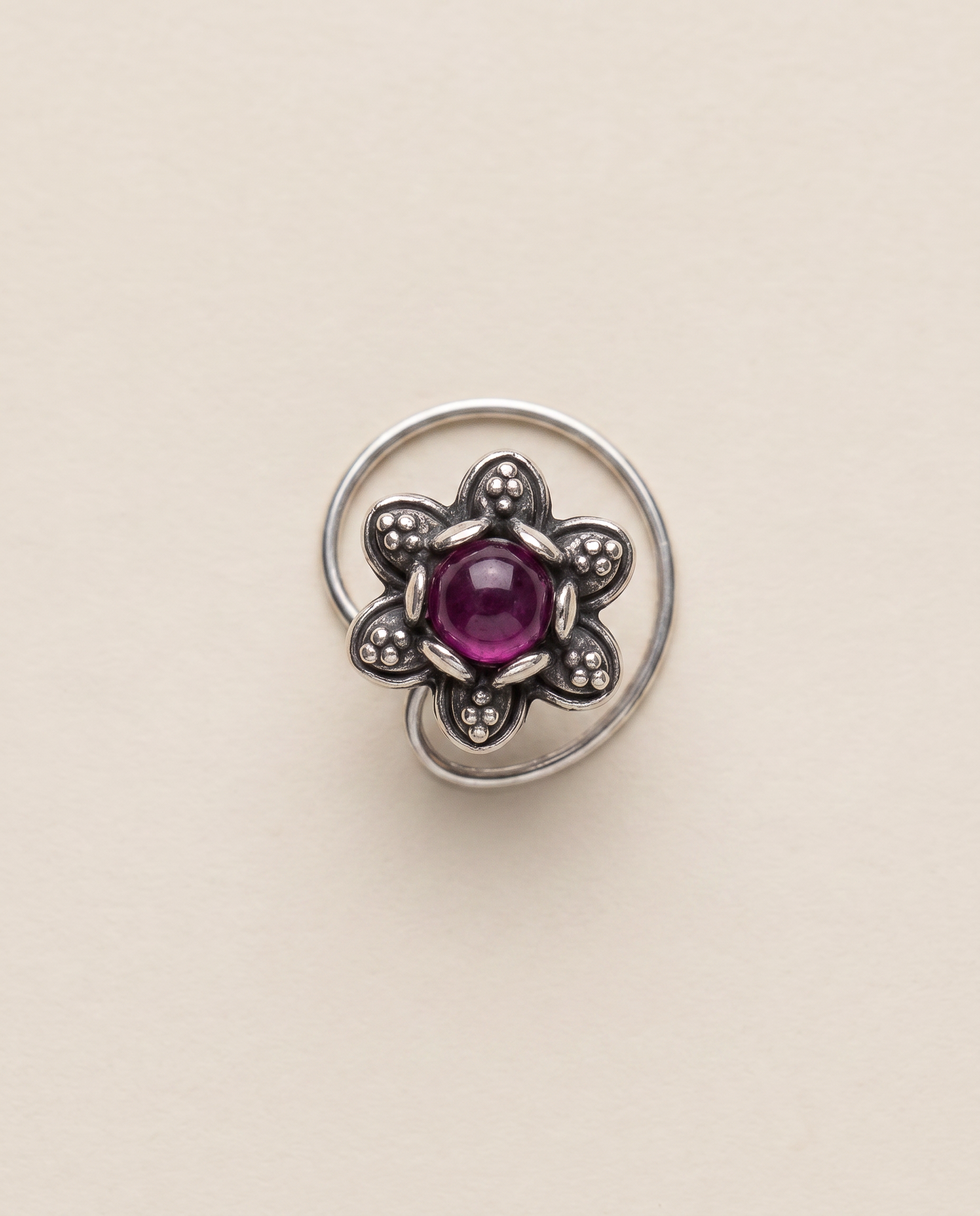 Divi oxidised silver-look floral nose pin with a deep magenta-purple centre stone and a curved wire fitting