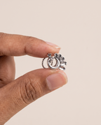 Morni peacock piercing nose pin held between fingertips in profile, showing its small size and its fitting