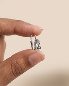 Morni peacock nose pin held between fingertips in profile, showing its small size and the flat U-shaped clip that needs no piercing