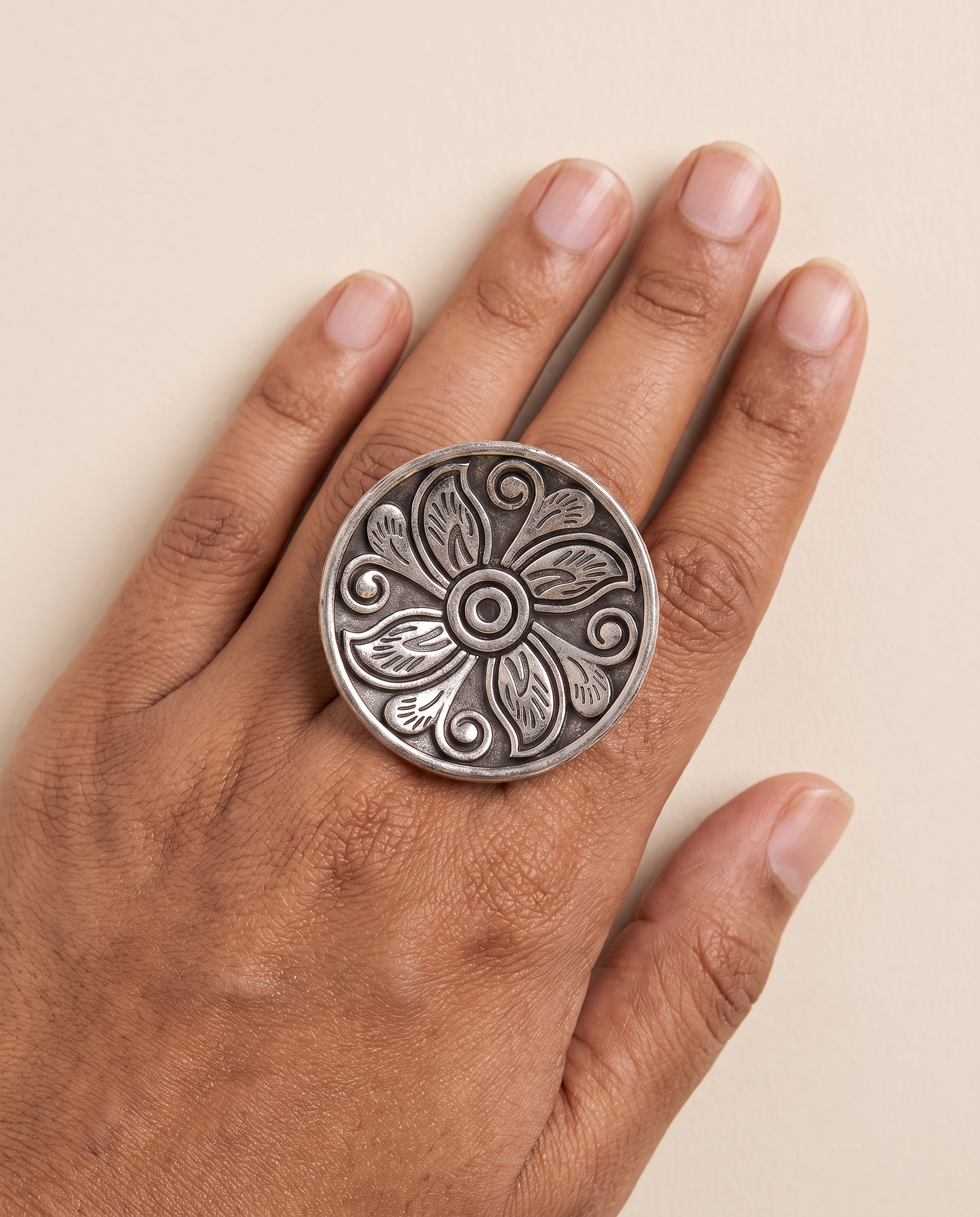 Ranchi engraved floral disc ring worn on the middle finger