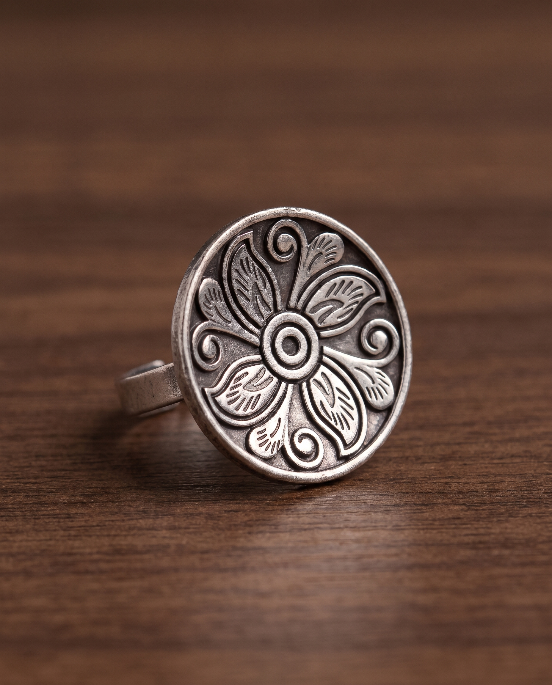 Close-up of the Ranchi engraved disc ring on walnut wood showing the depth of the engraving