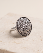 Close-up of the Vipra paisley dome ring on pale limestone showing the domed profile