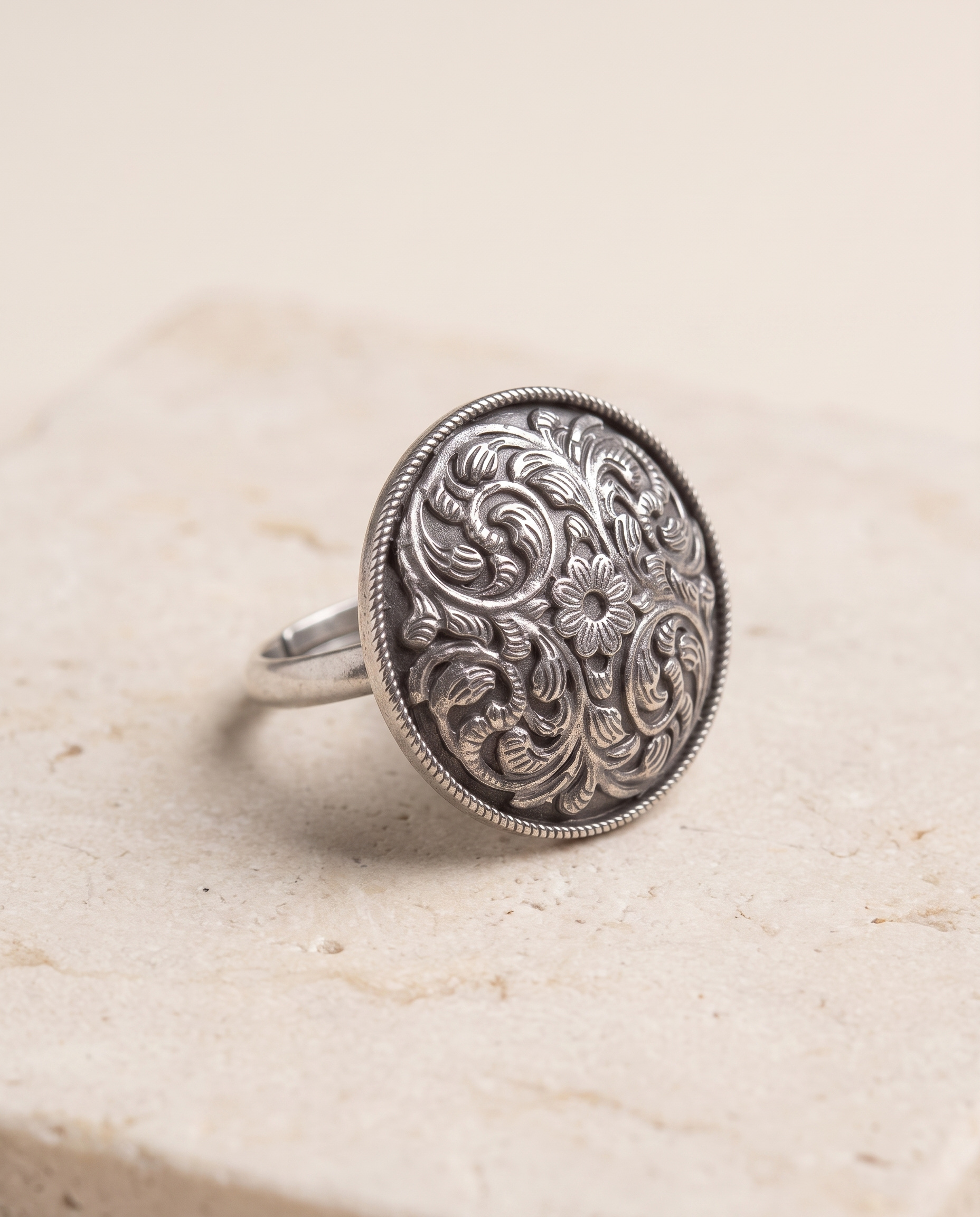Close-up of the Vipra paisley dome ring on pale limestone showing the domed profile