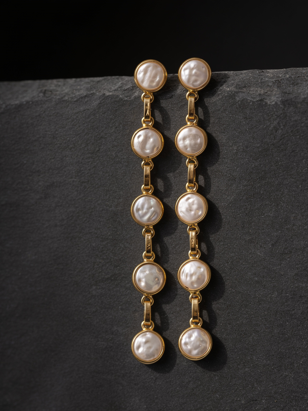 Five-pearl row drop earrings on a dark background