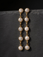 Five-pearl row drop earrings on a dark background