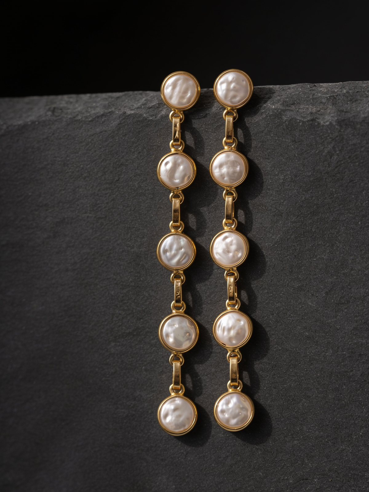 Five-pearl row drop earrings on a dark background