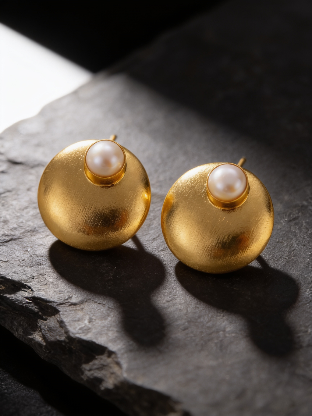 Gold-tone freshwater pearl dome stud earrings on a dark background