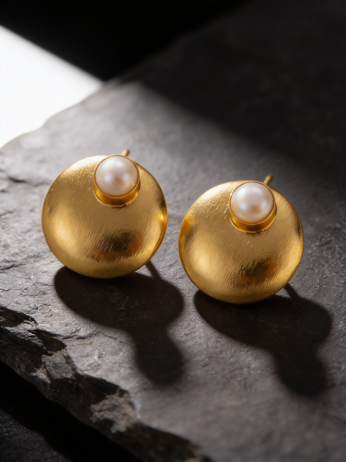 Gold-tone freshwater pearl dome stud earrings on a dark background