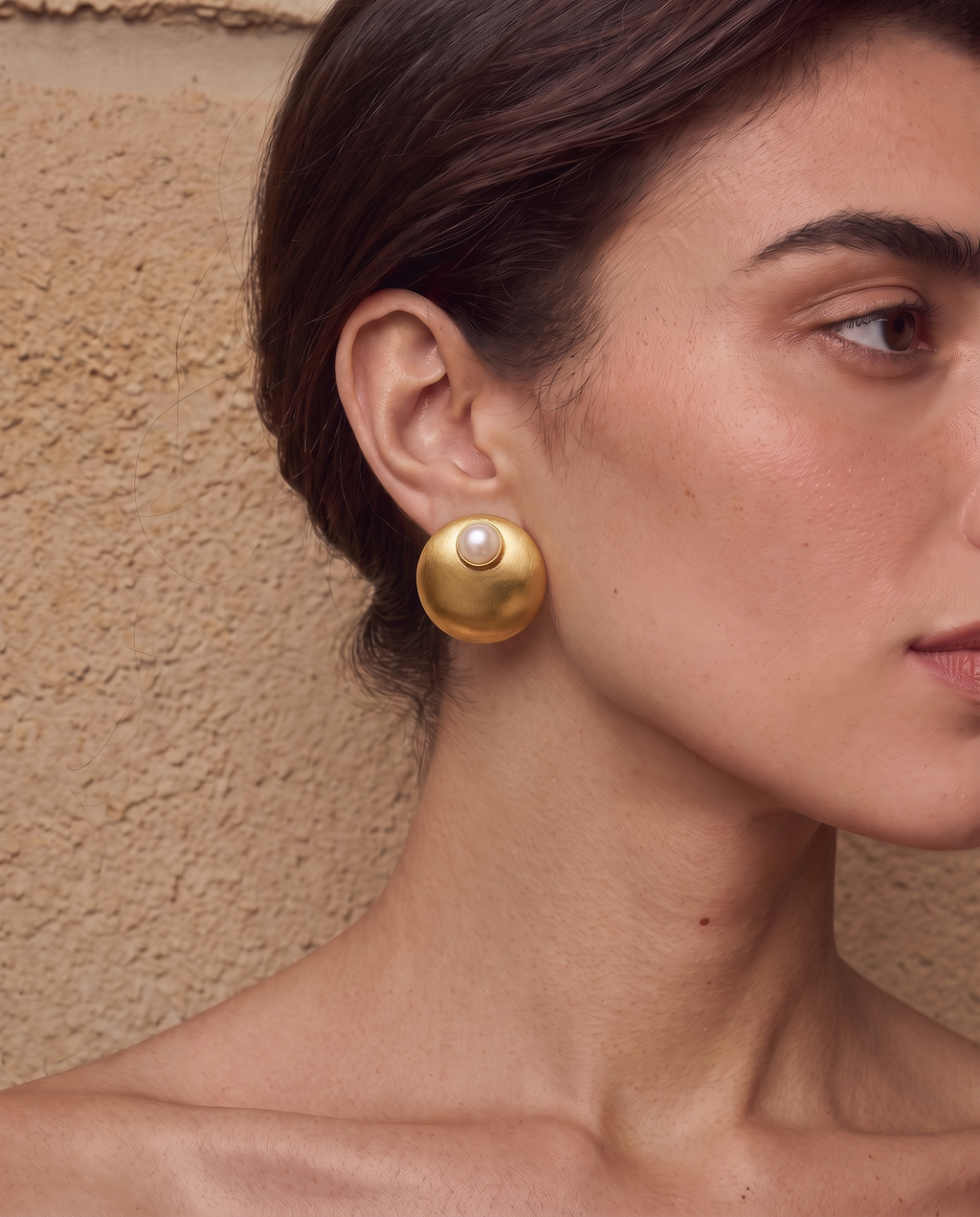 Gold-tone freshwater pearl dome stud earrings worn on a model