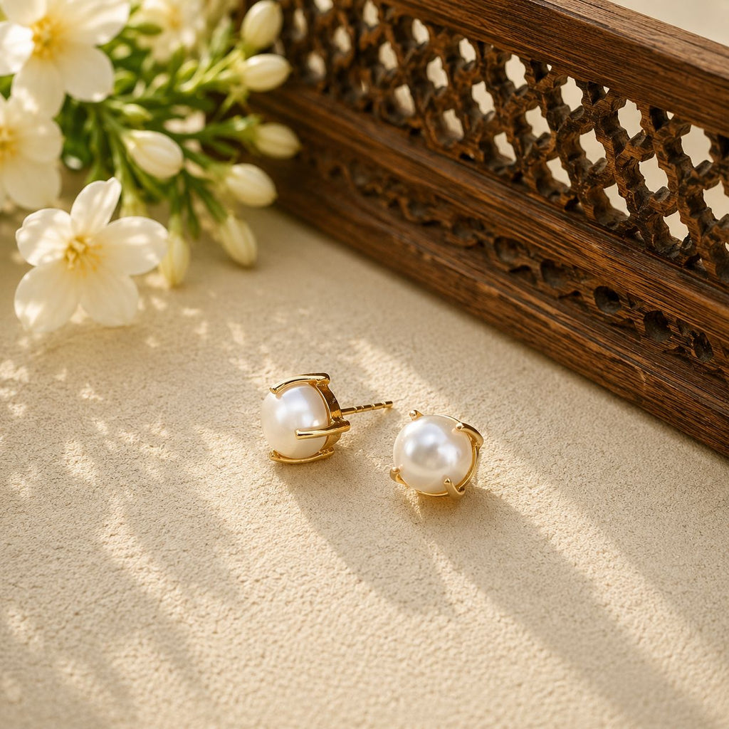Gold-tone freshwater pearl stud earrings styled with jasmine and carved wood