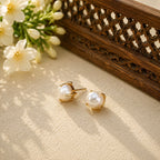 Gold-tone freshwater pearl stud earrings styled with jasmine and carved wood
