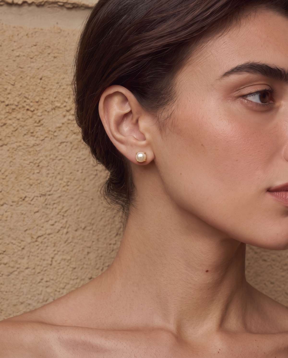 Gold-tone freshwater pearl stud earrings worn on a model