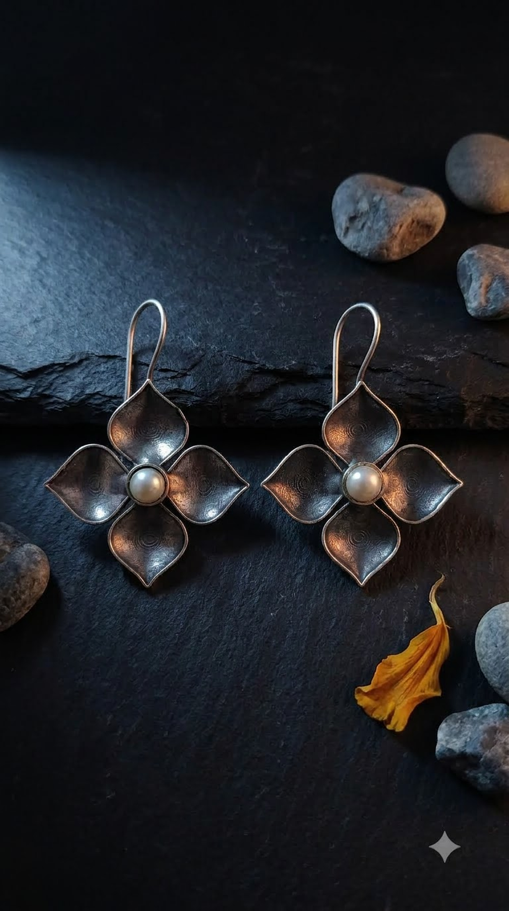 Silver-tone pearl petal drop earrings on a dark background
