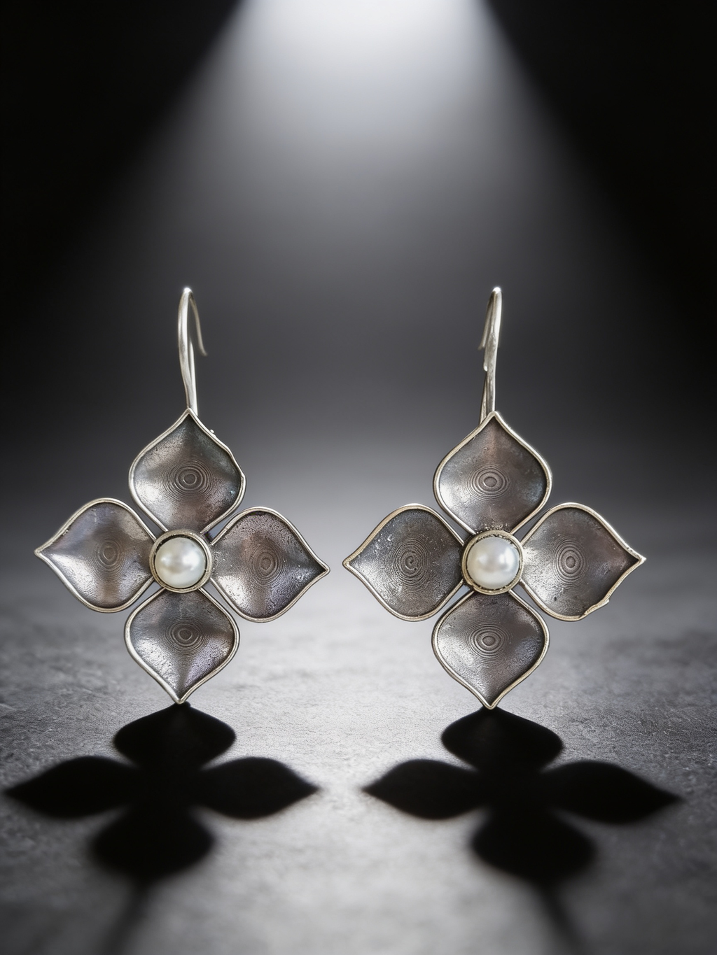 Silver-tone pearl petal drop earrings on a graphite studio backdrop