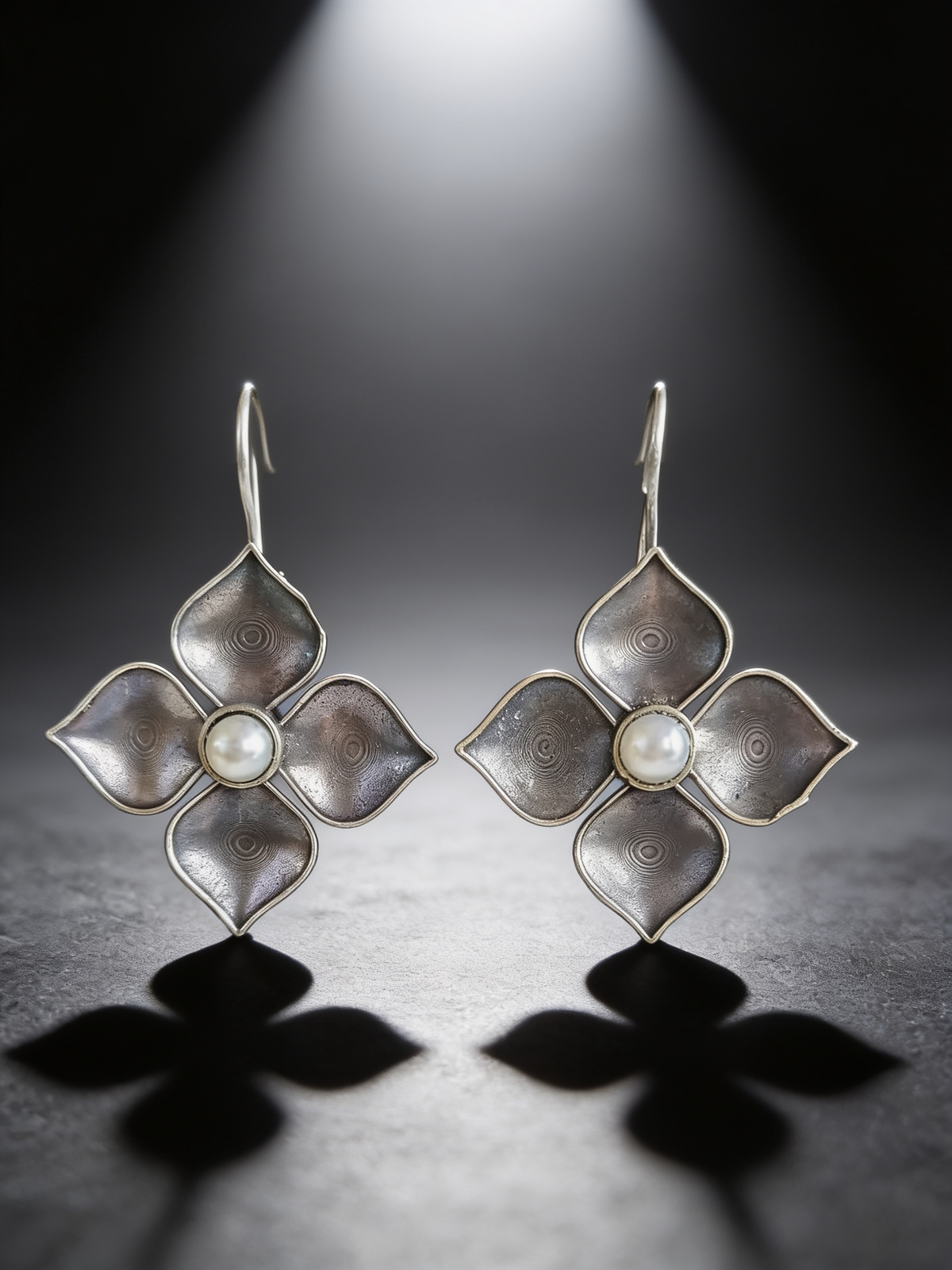 Silver-tone pearl petal drop earrings on a graphite studio backdrop