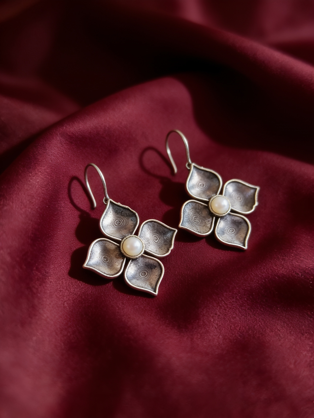 Silver-tone anti-tarnish brass drop earrings with pearls arranged like falling petals, styled on burgundy silk