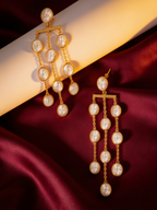 Long gold-tone anti-tarnish brass earrings with cascading strands of pearls, styled on burgundy silk