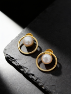 Round frame pearl stud earrings on a dark background