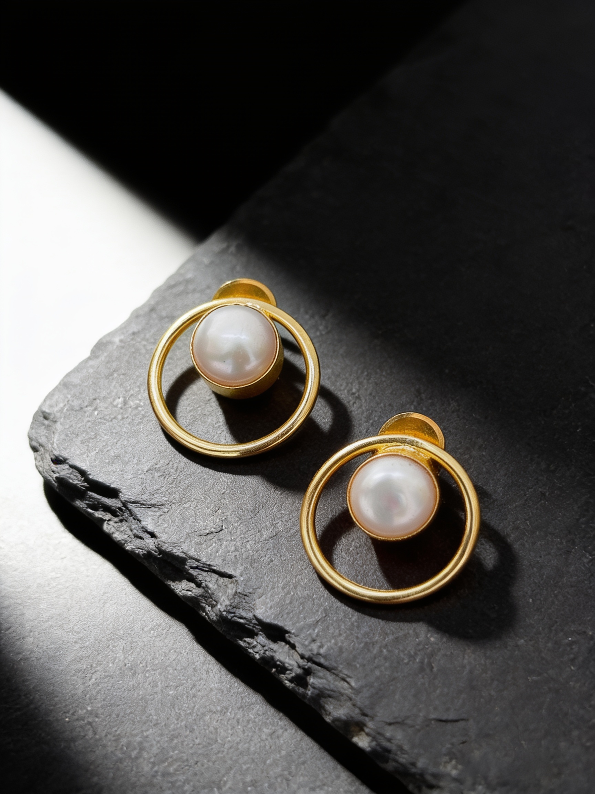 Round frame pearl stud earrings on a dark background
