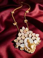 Gold-tone anti-tarnish brass necklace and earrings set with a mother-of-pearl peacock motif and pearls, styled on burgundy silk