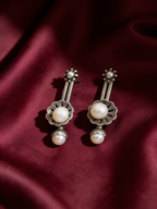 Oxidised silver-look brass earrings with an understated minimal shape, styled on burgundy silk