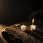 Gold-tone freshwater pearl drop earrings on a dark background