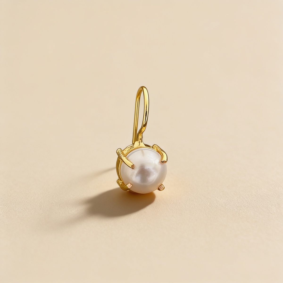 Gold-tone anti-tarnish brass hook earrings with a single freshwater pearl on a light background