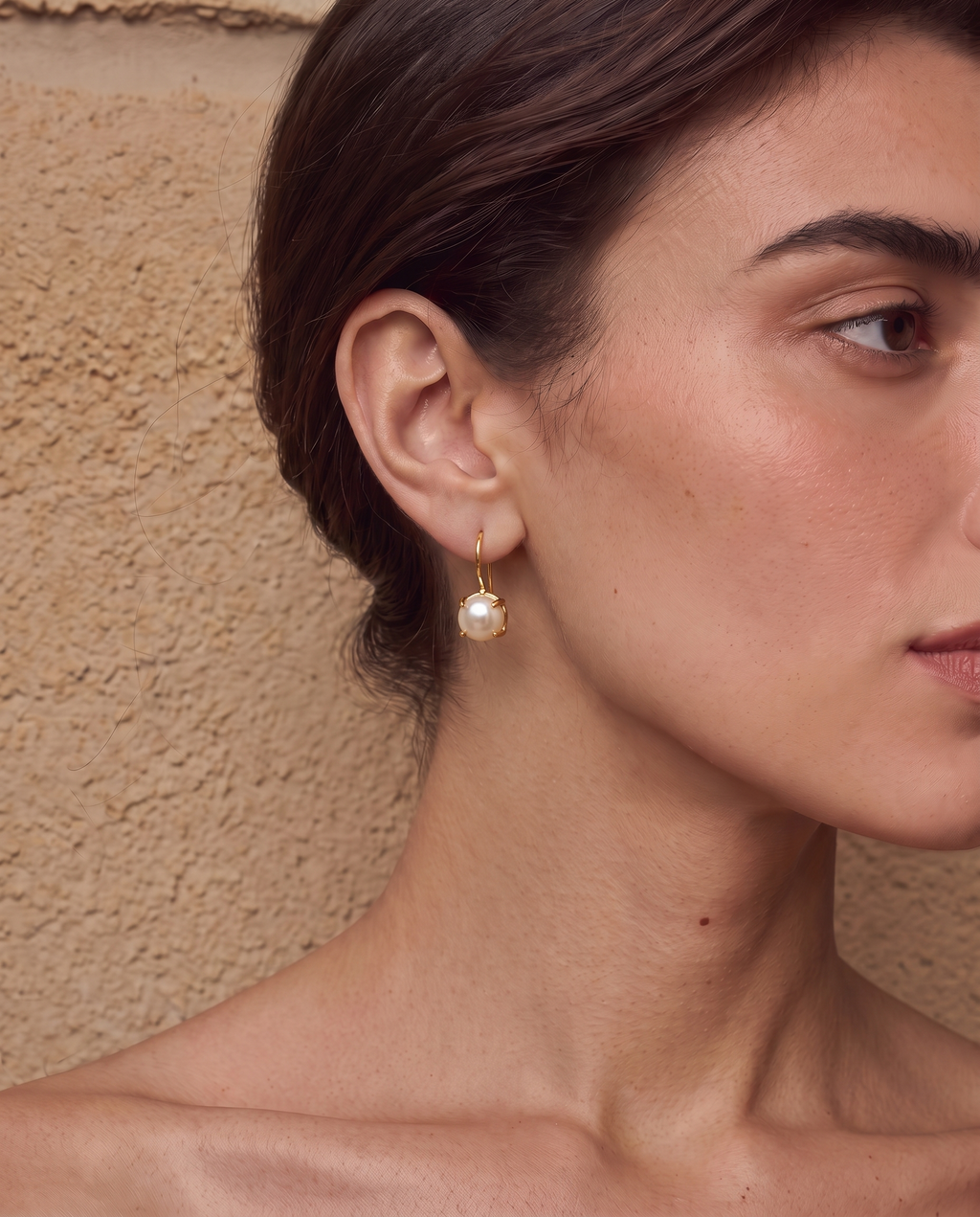 Gold-tone freshwater pearl drop earrings worn on a model