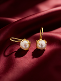 Gold-tone anti-tarnish brass hook earrings each with a single freshwater pearl drop, styled on burgundy silk
