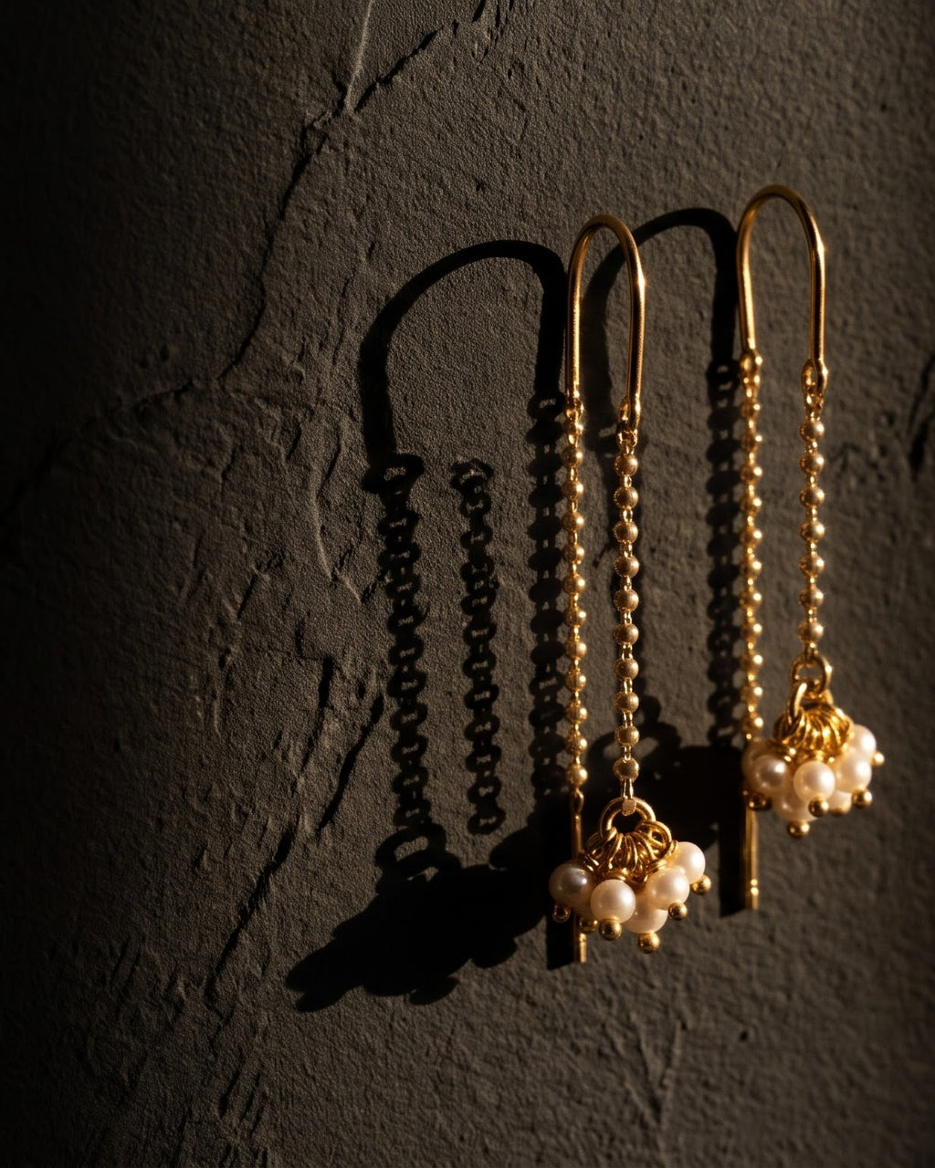 Sui dhaga pearl thread-through earrings on a dark background