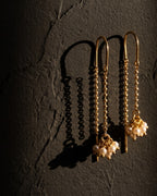 Sui dhaga pearl thread-through earrings on a dark background