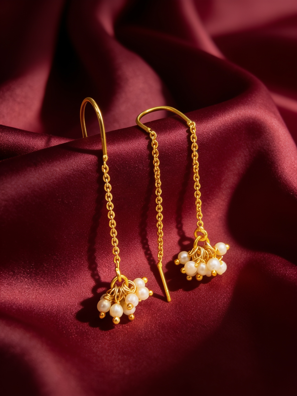 Gold-tone anti-tarnish brass thread-through sui-dhaga earrings each ending in a single pearl, styled on burgundy silk