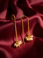 Gold-tone anti-tarnish brass thread-through sui-dhaga earrings each ending in a single pearl, styled on burgundy silk