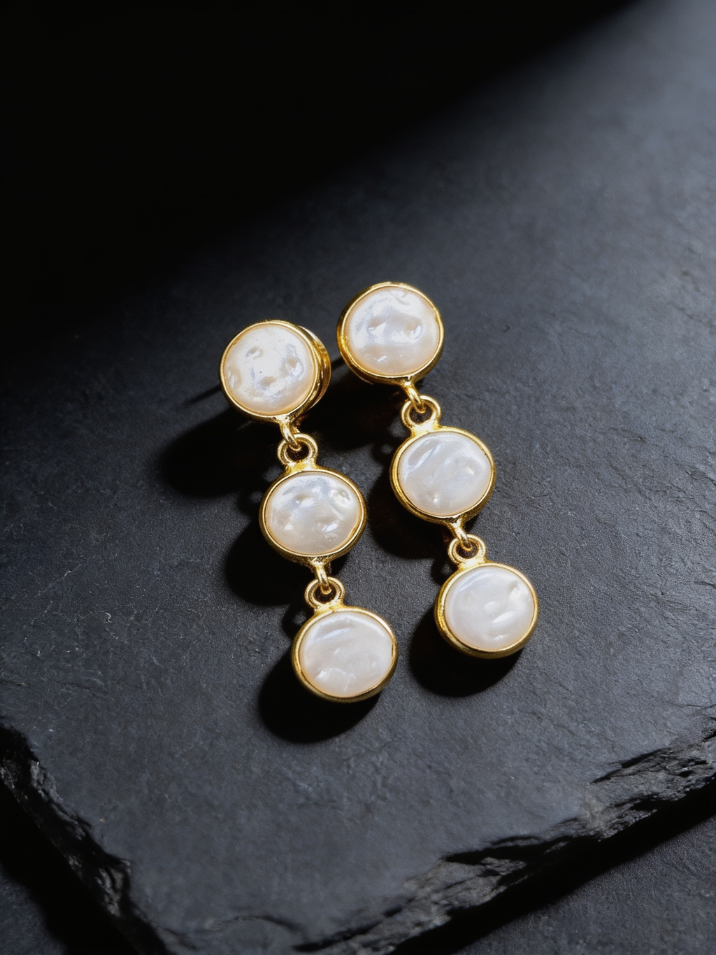 Trio pearl stud earrings on a dark background